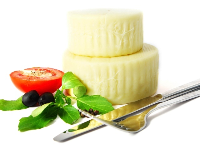 Сыр с помидором, столовыми приборами, оливками и зеленью на белом фоне