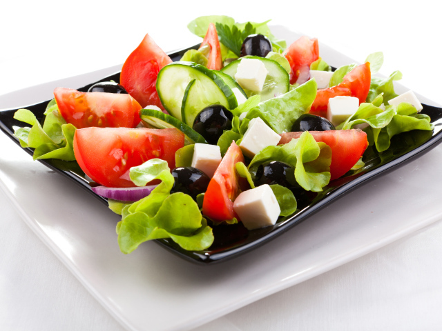 Греческий салат с сыром, помидорами и огурцами на белом фоне
