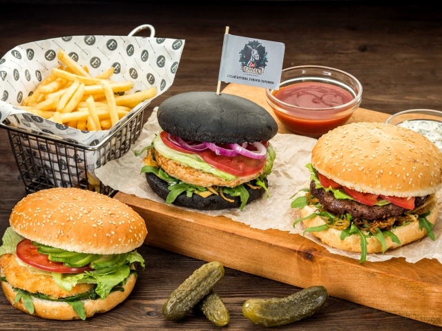 Гамбургеры с картофелем фри и солеными огурцами на столе 