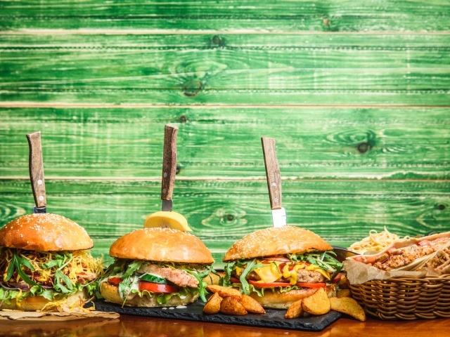 Гамбургеры с ножами на деревянном фоне