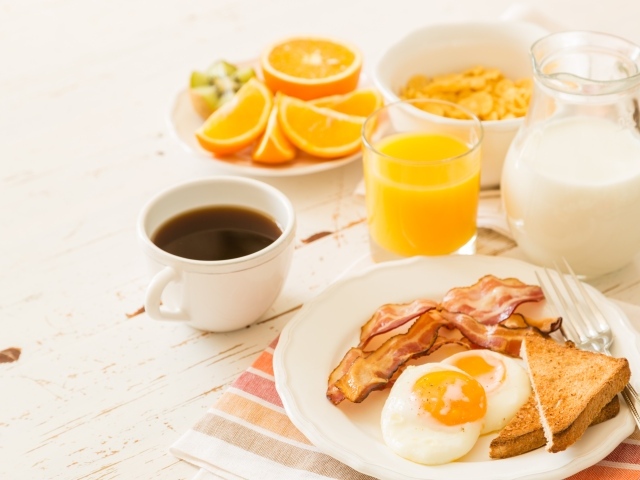 Сок, молоко, кофе, яичница и бекон на завтрак 