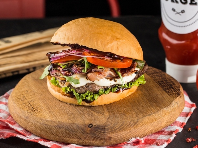 Большой аппетитный гамбургер на деревянной доске 