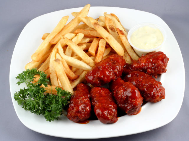 Тефтели в соусе с картофелем фри и петрушкой на тарелке