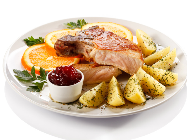 Картофель с мясом и кусочками апельсина на тарелке