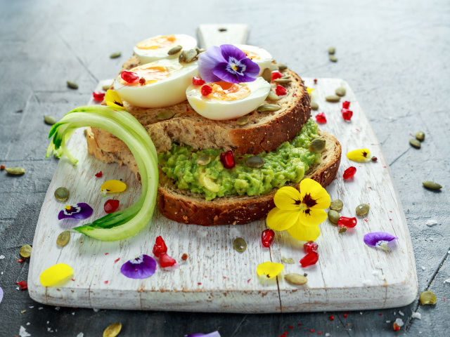 Сендвич с яйцом и цветами на доске