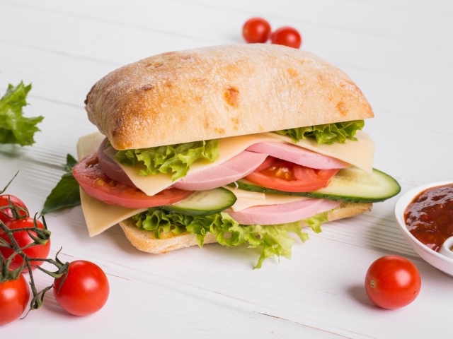 Сендвич с соусом и помидорами на столе 