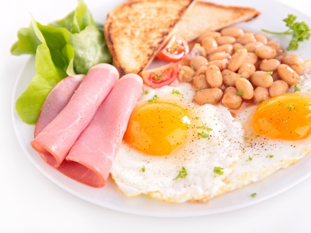 Яичница с беконом, гренками, фасолью и листьями салата на завтрак