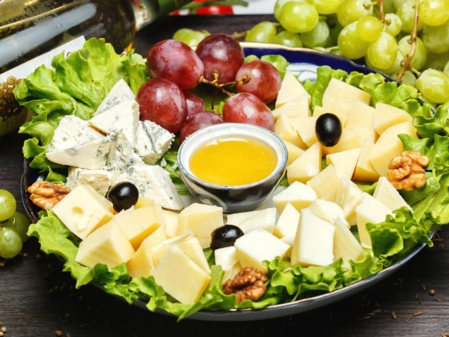 Нарезанный сыр на тарелке в виноградом 