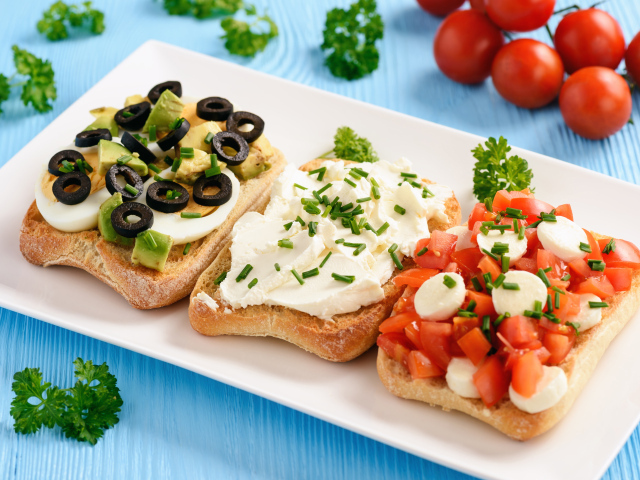 Три аппетитных бутерброда на столе с помидорами и петрушкой