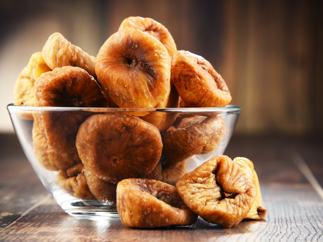 Инжир в стеклянной вазе на столе 