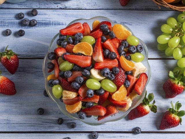Фрукты и ягоды в тарелке на столе 