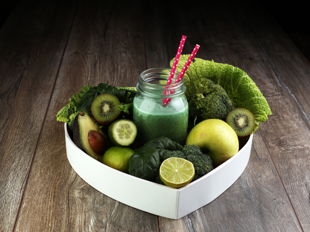 Зеленые овощи и фрукты в тарелке с баночкой смузи