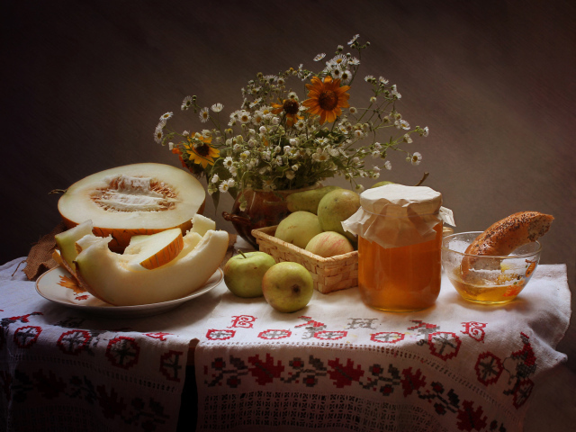 Сочная дыня с яблоками на столе с медом и букетом цветов