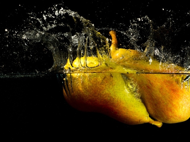 Груши в воде с брызгами на черном фоне