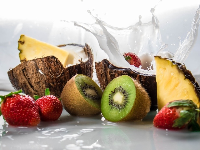 Тропические фрукты кокосы, ананасы и киви на белом фоне с клубникой