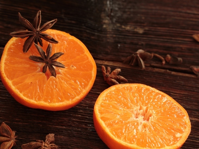 Две половины апельсина на деревянном столе с бадьяном