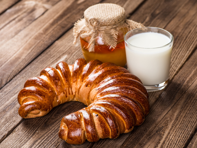 Свежая выпечка на столе с медом и стаканом молока
