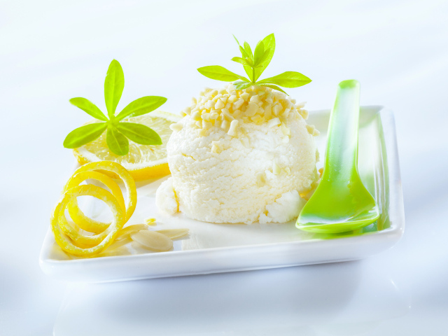 Шарик лимонного мороженого с фисташками с зеленой ложкой