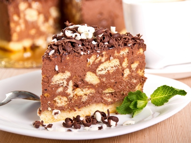 Кусок торта с шоколадом и листьями мяты на тарелке