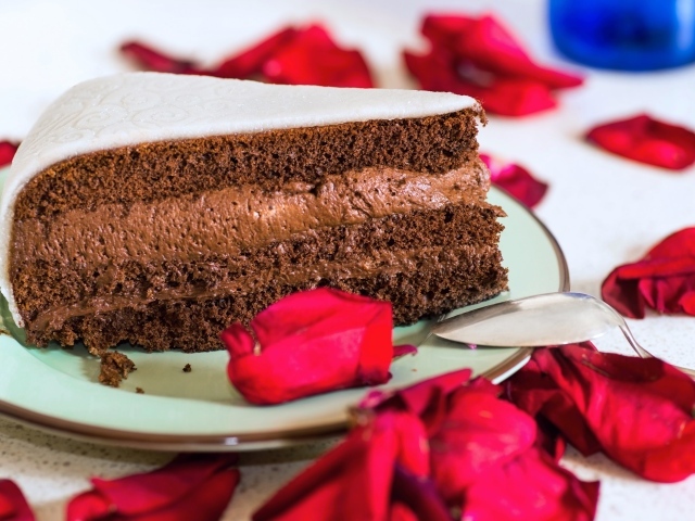 Кусок торта с шоколадным кремом и красными лепестками розы