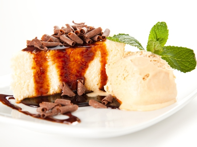 Кусок чизкейка с шоколадом и шариком мороженого на белой тарелке 