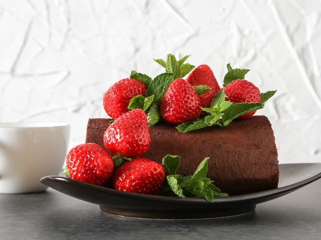 Кусок шоколадного торта со свежей клубникой на тарелке