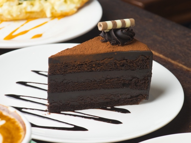 Кусок аппетитного шоколадного торта на белой тарелке