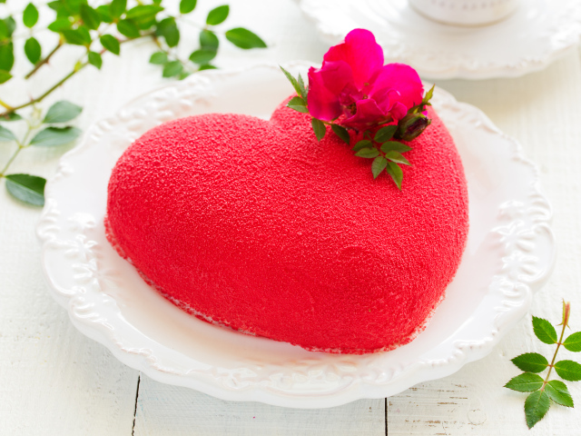Красивый торт в форме сердца на белом блюде с красным цветком