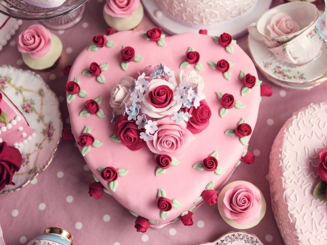 Красивый праздничный розовый торт в форме сердца украшен цветами