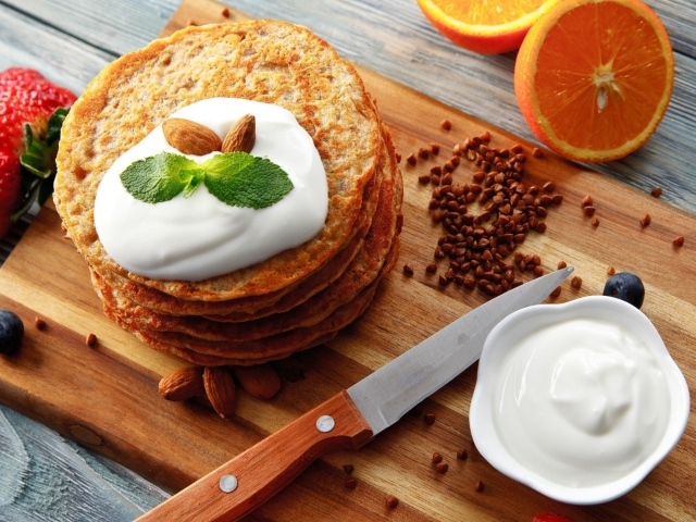 Гречневые оладьи со сметаной на разделочной доске