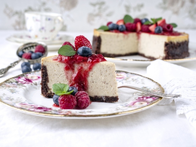 Чизкейк на столе с ягодами малины, черники и клубники