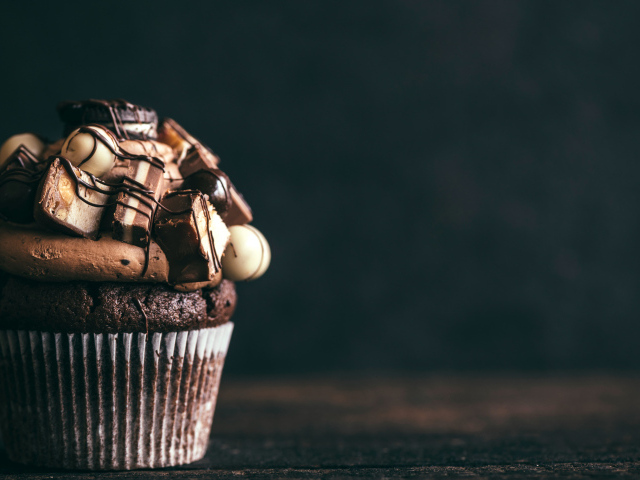 Шоколадный кекс с кремом и конфетами на сером фоне