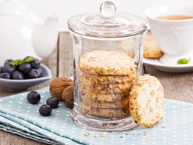 Печенье в стеклянной банке на столе с орехами и черникой