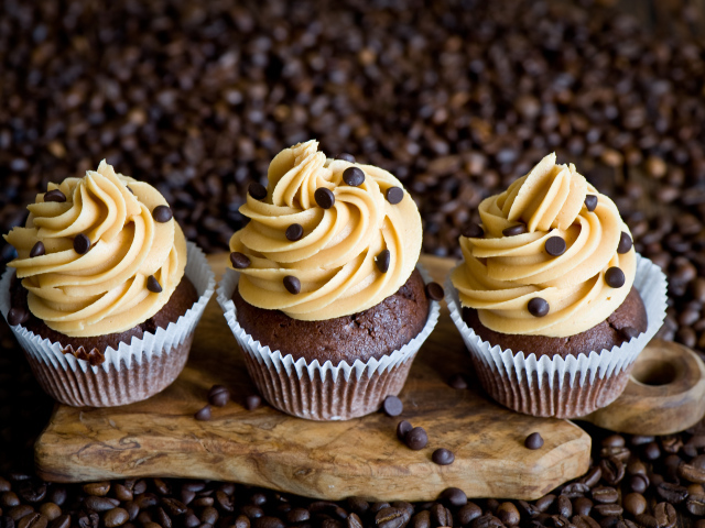 Кексы с кремом и зернами кофе на столе 