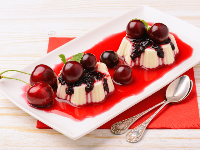 Десерт с желе и ягодами черешни на тарелке с сиропом