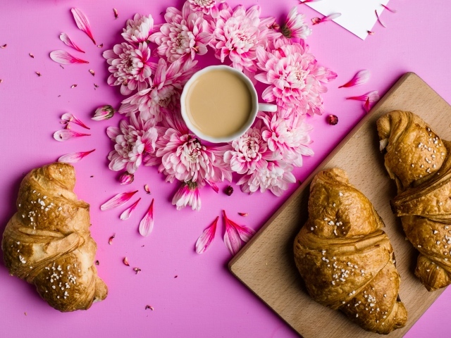 Свежие круассаны на столе с чашкой какао и цветами хризантемы
