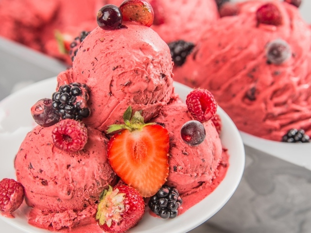 Шарики фруктового мороженого на тарелке с ягодами 
