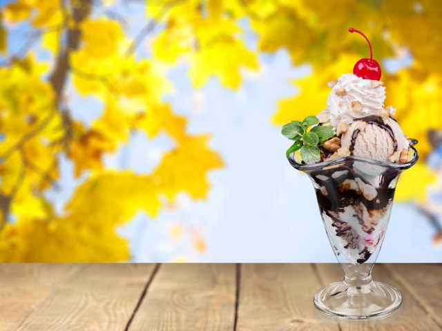 Мороженое в креманке с вишенкой на фоне желтых листьев