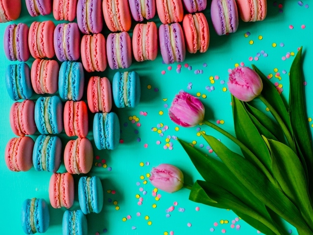 Разноцветные десерты макарун на столе с тюльпанами