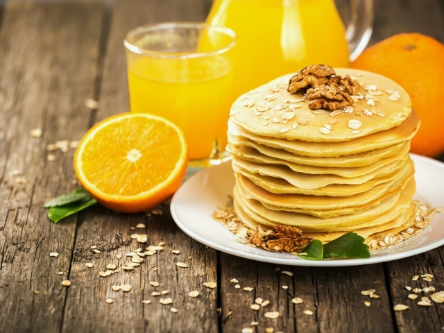 Оладьи с орехами на столе с апельсиновым соком и апельсинами
