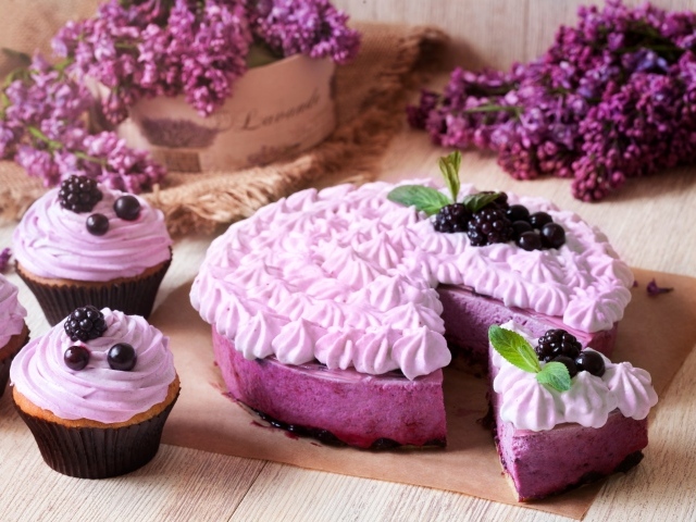 Пирог с кремом и вкусными кексами с черникой на столе с цветами сирени