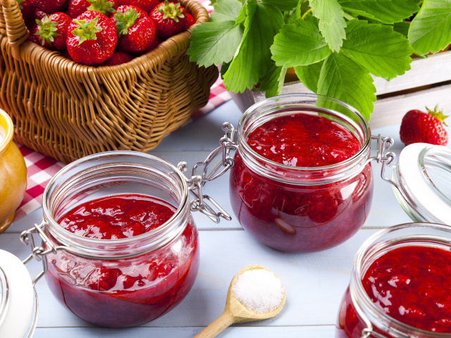Клубничное варенье в стеклянных баночках на столе  ягодами