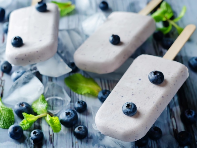 Вкусное мороженое с ягодами черники на столе с кусочками льда