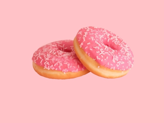 Два пончика с глазурью на розовом фоне