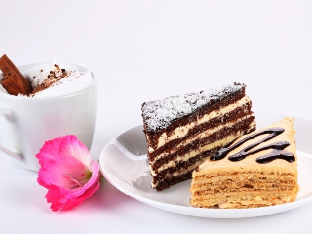 Два куска торта на столе с чашкой кофе и розовым цветком