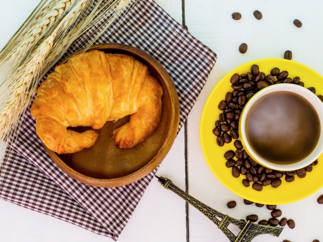 Чашка кофе на столе со свежим круассаном