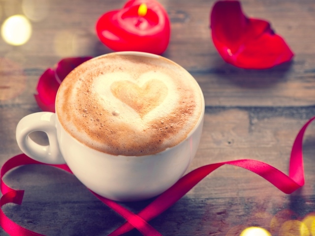 Чашка кофе на столе с красной свечой и лентой