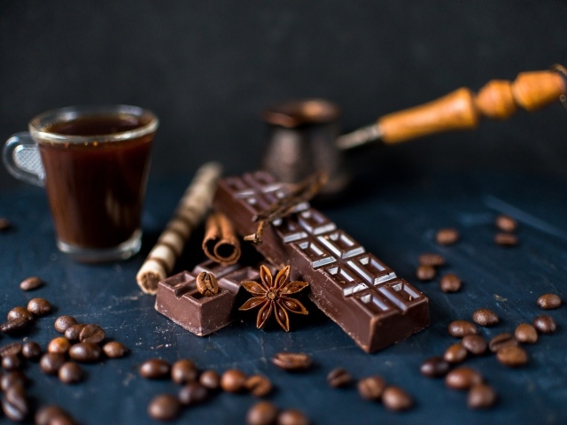 Чашка кофе на столе с шоколадом и зернами кофе