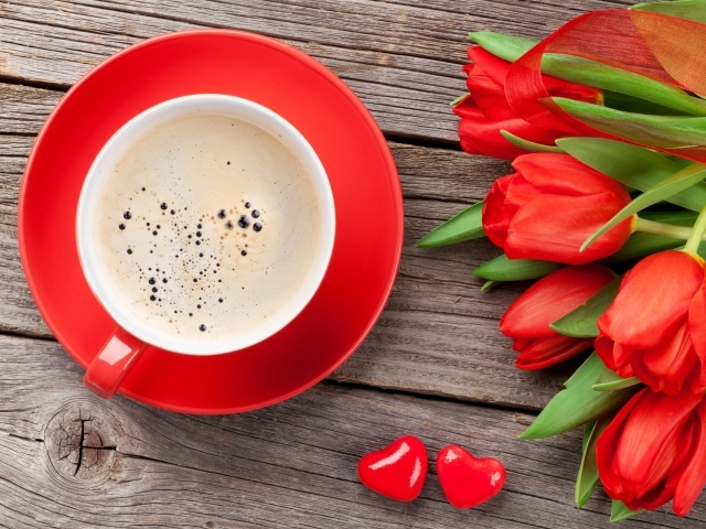 Чашка кофе с красными тюльпанами на деревянном столе 