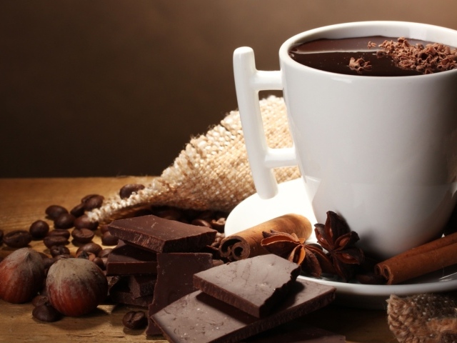 Чашка горячего шоколада на столе с корицей, бадьяном и фундуком